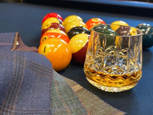 Fabric samples on pool table with pool table balls and glass of whiskey